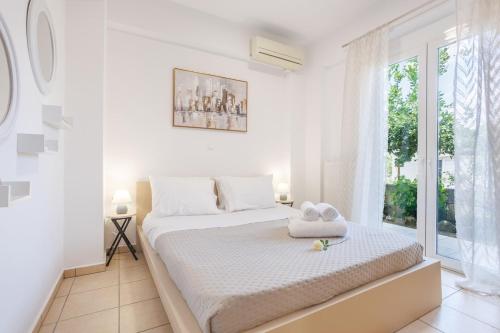 a white bedroom with a bed and a window at Arivaro Apartment in Souda