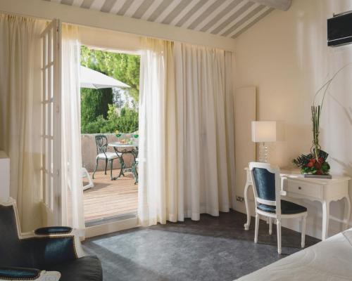 a bedroom with a desk and a table and a patio at Auberge de Cassagne & Spa in Le Pontet