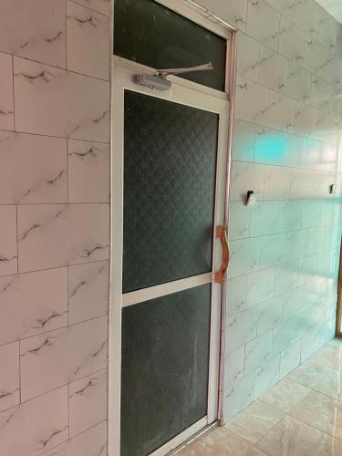 a sliding glass door in a bathroom with white tiles at Omuka owaawe resort in Biguri