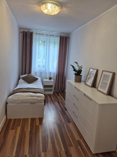 a bedroom with a bed and a dresser and a window at Apartament przy Dworcu Sanok in Sanok