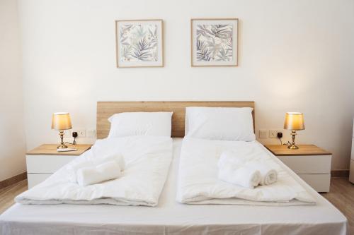 a bedroom with two beds with white sheets and two lamps at Staytopus Kenn is Sur - Citadel Victoria Gozo Hideaway - Pool in Victoria