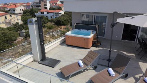 a patio with a hot tub and chairs and an umbrella at Luxury Loft Apartment Mandre in Mandre