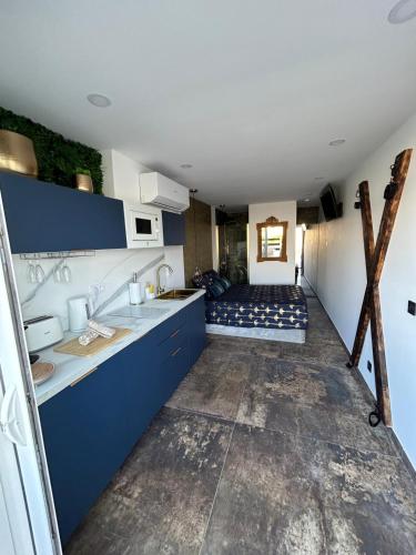 a kitchen with blue cabinets and a bed in a room at La suite des charmes - village naturiste - port nature 2 coursives in Cap d'Agde
