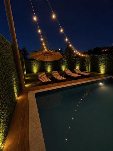 a swimming pool with chairs and an umbrella at night at Wooden Villa Eilin 3 in Tirana