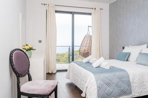 a bedroom with a bed and a chair and a window at Canhas Ocean View in Ponta do Sol