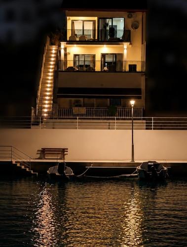 a building on the water with a bench on a dock at Casa Amor in Neum