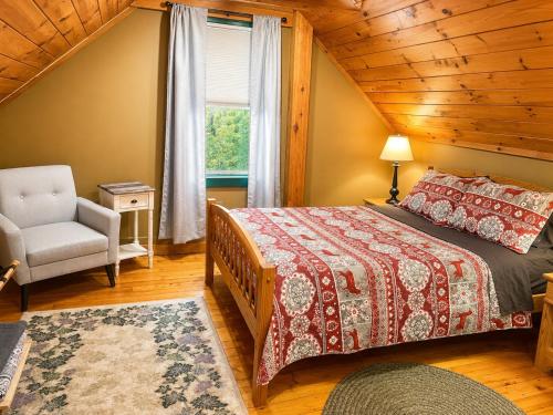 a bedroom with a bed and a chair and a window at Allegory Inn in Twin Mountain