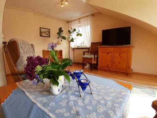 a living room with a table with a vase of flowers at Ferienwohnung Purwins in Ebermannstadt