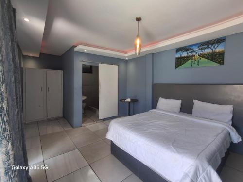 a bedroom with a large bed and a bathroom at Moonlight Guesthouse in Bloemfontein