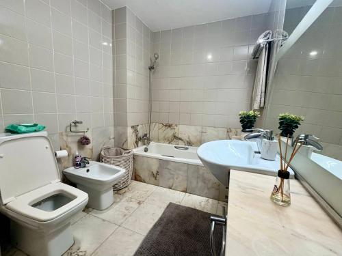 a bathroom with a toilet and a sink and a tub at Polana View Apartment I in Maputo
