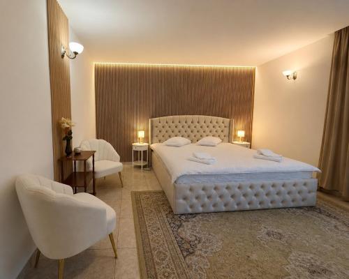 a bedroom with a white bed and two chairs at Vila Iepurasul Sinaia in Sinaia