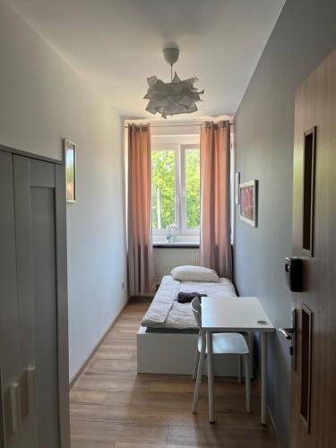 a bedroom with two beds and a table and a window at Fajrant Rooms Katowice in Katowice
