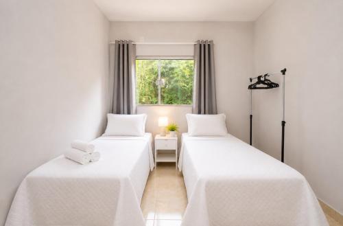 two beds in a room with a window at Quinta do Sol Condominium - Pirenópolis in Pirenópolis
