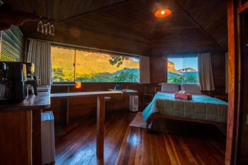 a bedroom with a bed and a desk and a window at Pousada Casa da Trilha in Vale do Capao