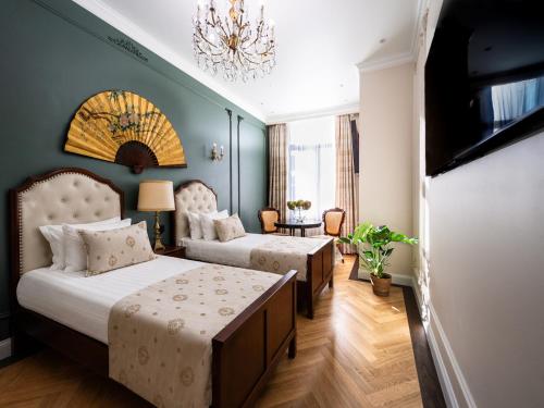 a bedroom with two beds and a chandelier at Strands Of Time Hotel Bruges in Bruges