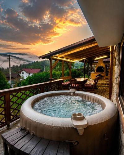a hot tub on a deck with a sunset in the background at Vila Iepurasul Sinaia in Sinaia