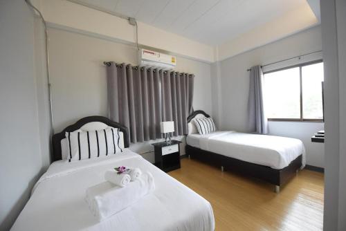 a hotel room with two beds and a window at Mont Place Donmuang in Ban Don Muang (1)