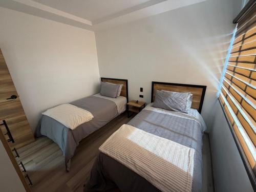 two beds in a small room with a window at Suite Vlady in Cuenca
