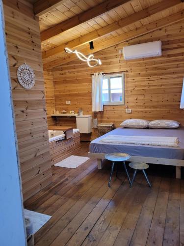 a bedroom with a bed and a wooden wall at Serenity Cabin in Dalia in Dāliyat el Karmil