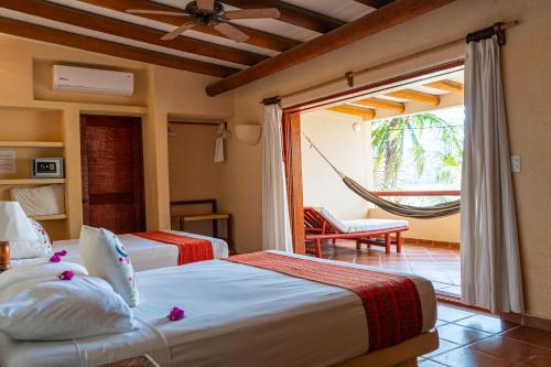 a hotel room with two beds and a hammock at Hotel Catalina Beach Resort in Zihuatanejo