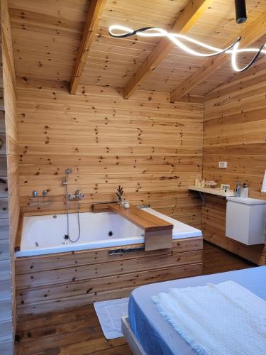 a bathroom with a tub in a wooden wall at Serenity Cabin in Dalia in Dāliyat el Karmil