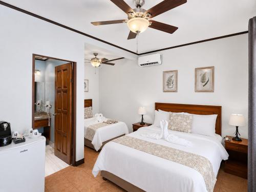 a bedroom with two beds and a ceiling fan at Hotel Espadilla Gardens in Quepos