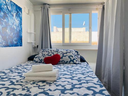 a bedroom with a bed with a heart pillow and towels at Ático Cádiz Suite in Cádiz