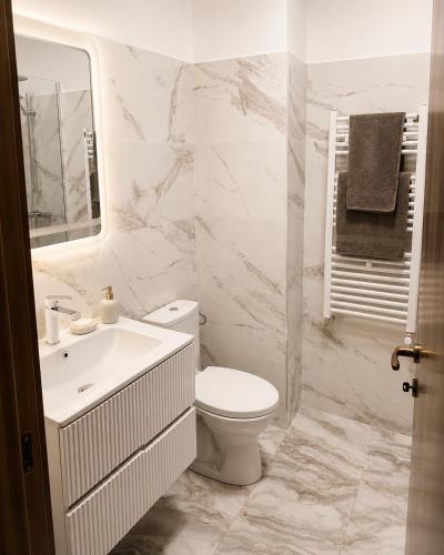 a white bathroom with a toilet and a sink at Rion Apartments in Saturn