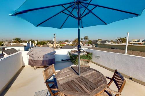 a table and chairs with an umbrella on a roof at Gull Cottage in Seal Beach