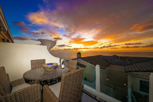 a balcony with a table and chairs and a sunset at San Clemente Ocean Luxury Bluff Top in San Clemente