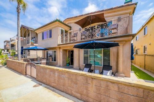 a house with a balcony with chairs and an umbrella at Palm Tree Getaway in Newport Beach
