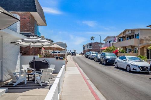a sidewalk with a table and an umbrella and parked cars at Newport Coastal Compound in Newport Beach