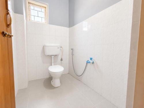 a white bathroom with a toilet and a window at Hi Hostels Shillong in Shillong