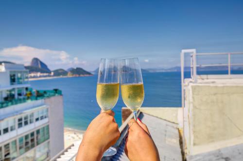 a person holding up two glasses of wine at Rio Design Copacabana Hotel in Rio de Janeiro