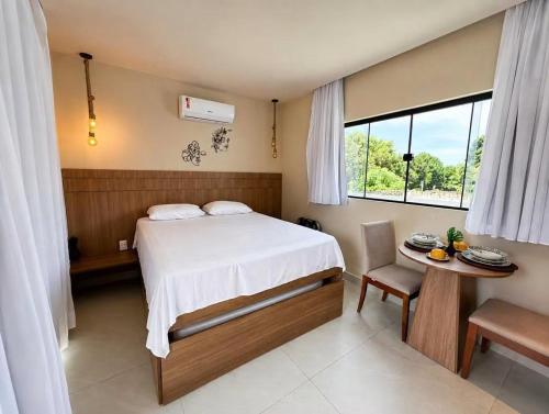 a bedroom with a bed and a table and a window at LAWAKE House pipa Studios e apartamentos nomads in Pipa