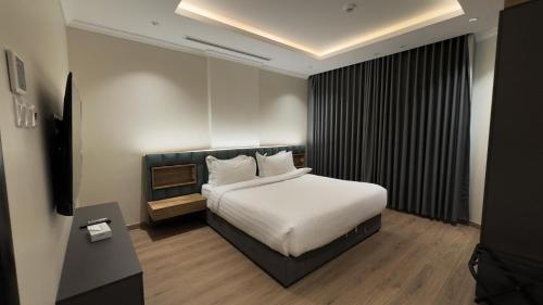 a hotel room with a bed and a television at Mirada Purple Najran Hotel in Najran