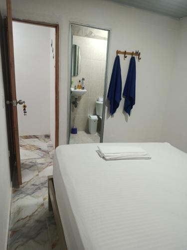 a white bed in a room with a bathroom at Los Clemones in Rincón