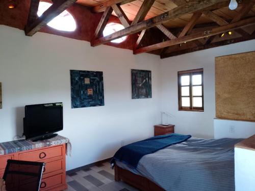 a bedroom with a bed and a flat screen tv at Off-grid mountain house with a view La Manchoza in Tapalpa