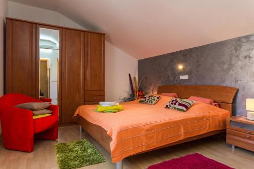 a bedroom with a bed and a red chair at Guesthouse Ivona in Dubrovnik