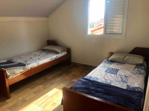 two beds in a small room with a window at Catarina Condomínio Clube in Mairinque