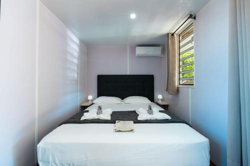 a bedroom with a white bed with two swans on it at Fare AGT Moorea in Afareaitu