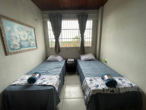 two twin beds in a room with a window at Flat Amarração Shopping in Luis Correia