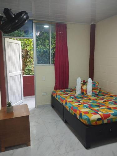 a bedroom with a bed with a colorful comforter at Hotel GinaMar Ladrilleros in Buenaventura