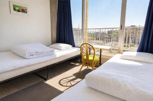 a room with two beds and a table and a balcony at Sakura Hostel Asakusa in Tokyo