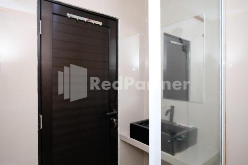 a bathroom with a black door and a sink at As Waru Hotel RedPartner in Palang-Putih