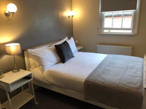 a bedroom with a bed with white sheets and a window at The Coachmakers Arms in Wallingford
