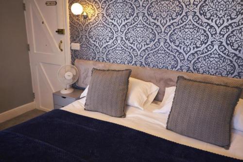 a bedroom with a bed with two pillows and a wall at The Coachmakers Arms in Wallingford