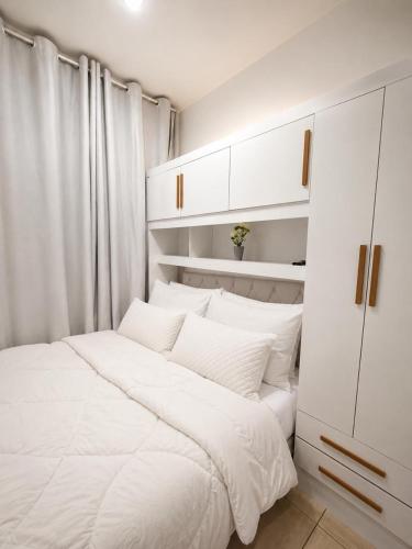 a bedroom with a white bed and white cabinets at Refúgio Beira Mar Na Praia da Tartaruga in Rio das Ostras