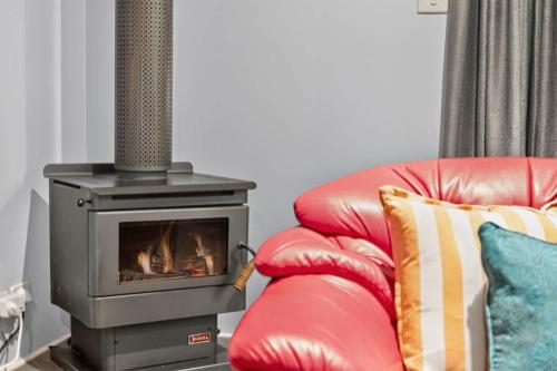 a fireplace and a red leather chair with a speaker at The Brynes Hideaway - On Brynes Road in Goolwa