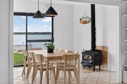 a dining room with a table and a wood stove at Barnacles Shack - Mills Road in Hindmarsh Island